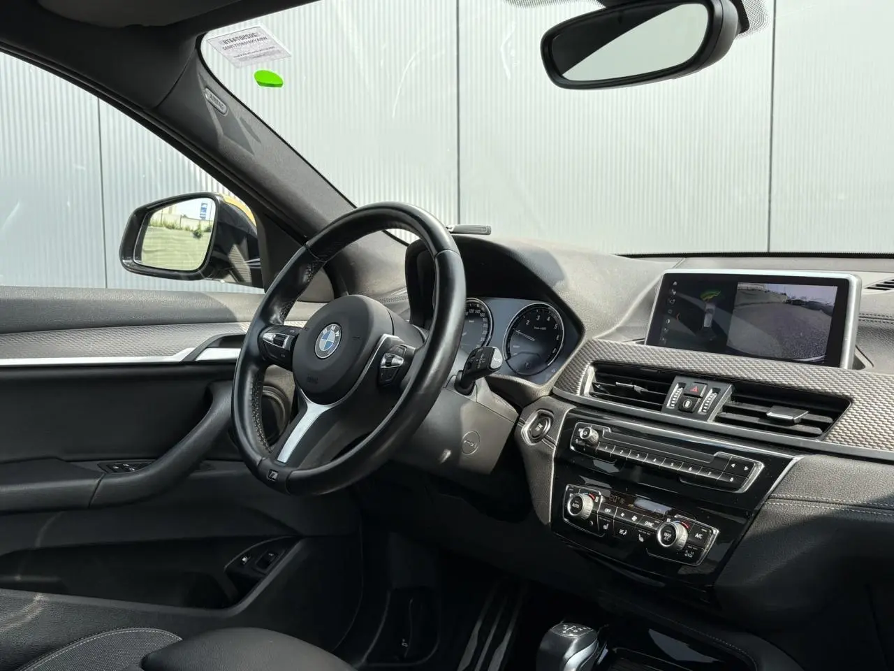 Vue intérieure côté conducteur du BMW X2 2021 avec volant M cuir, écran GPS et tableau de bord noir.