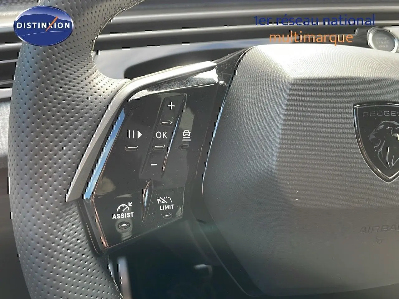 Gros plan sur le volant perforé noir du Peugeot 3008 2025 avec commandes intégrées et logo lion central.