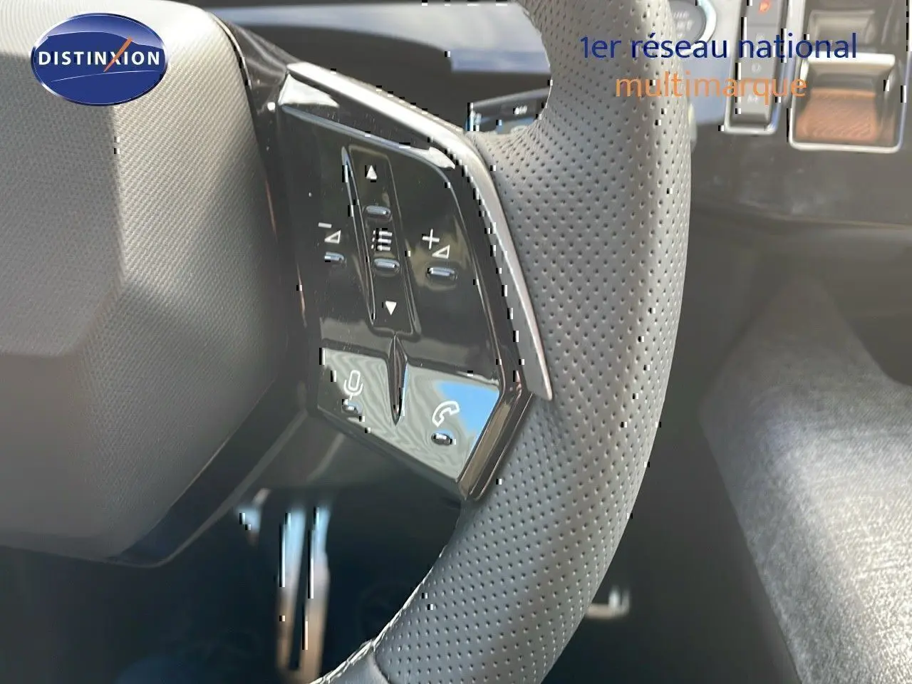 Gros plan sur le volant perforé avec commandes intégrées du Peugeot 3008 bleu Ingaro métal toit noir, version hybride 2025.