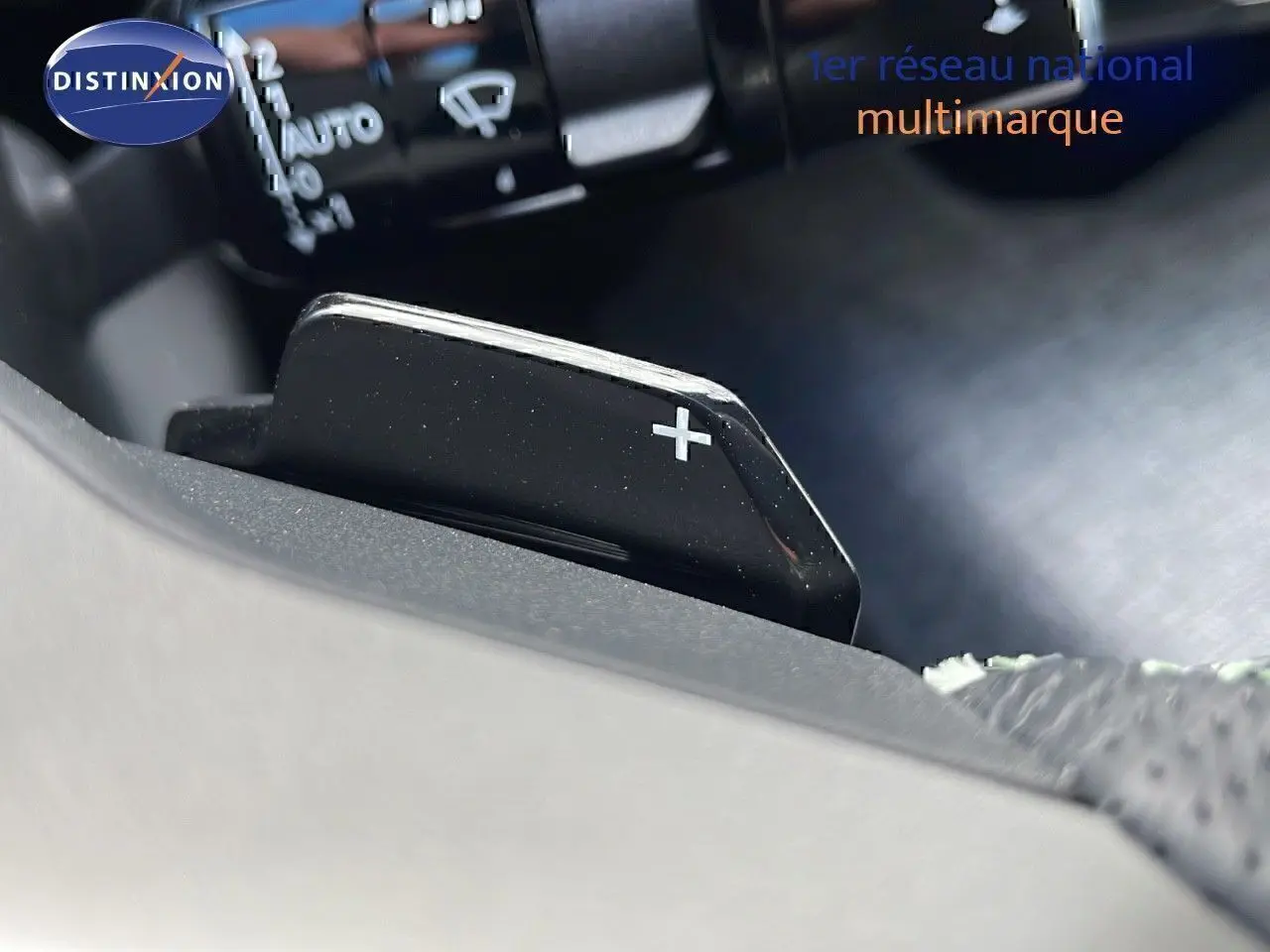 Gros plan sur la palette de changement de vitesse + du Peugeot 3008 hybride 2025, intérieur noir.