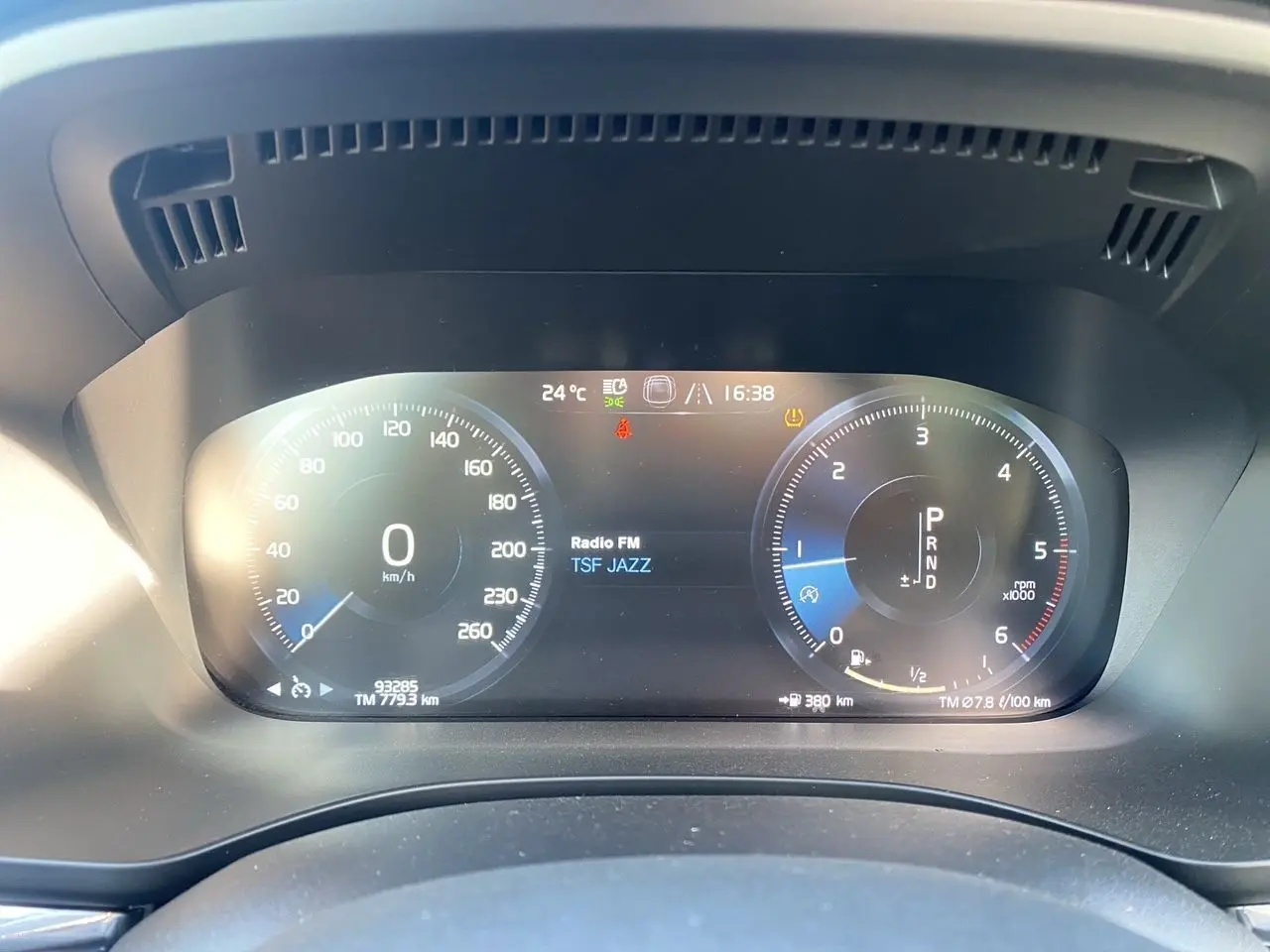 Tableau de bord numérique du Volvo XC60 blanc 2019, affichant vitesse, régime et radio TSF Jazz.