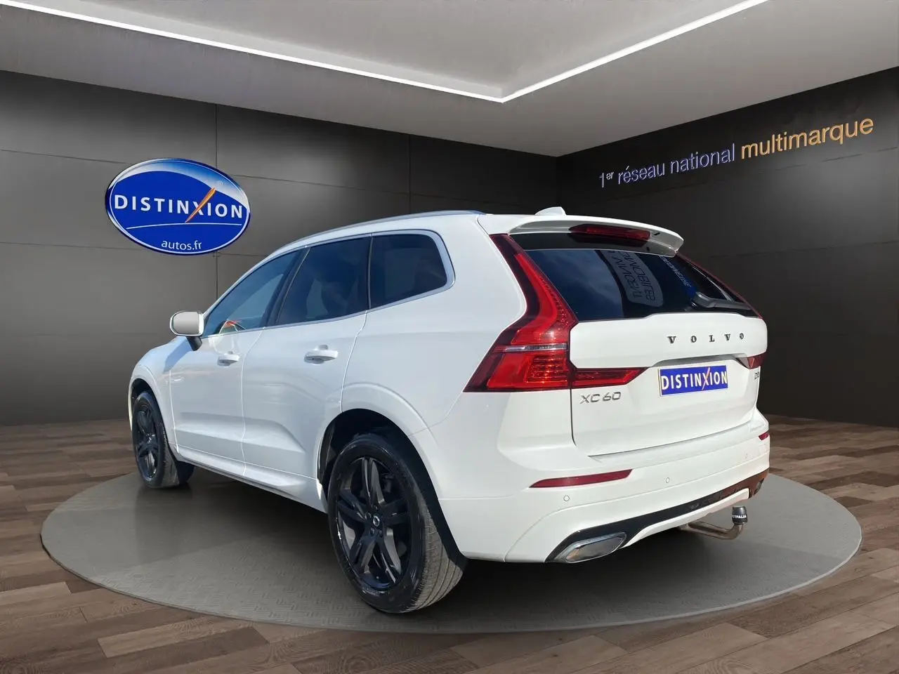 Vue 3/4 arrière droite du Volvo XC60 blanc 2019 avec jantes noires et feux arrière LED distinctifs.