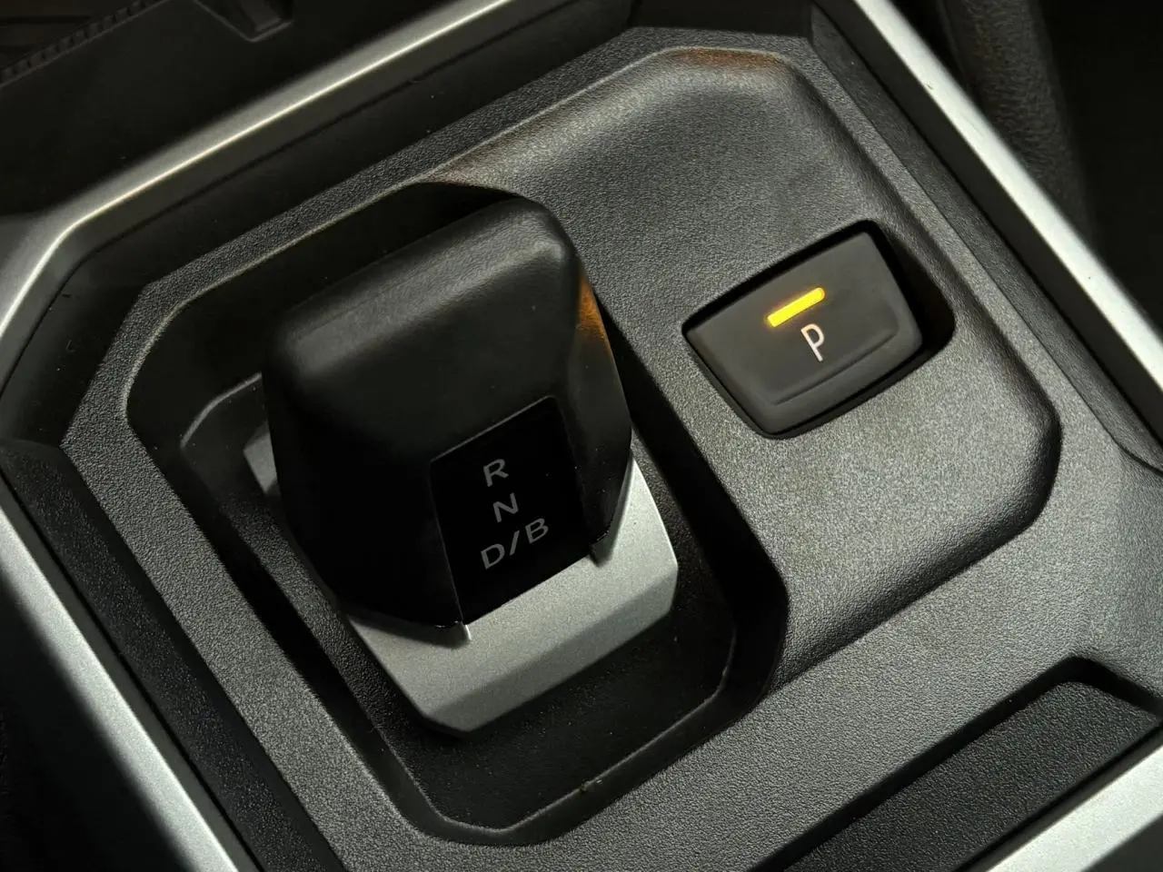 Gros plan sur la commande de boîte automatique et le bouton de frein de stationnement électrique du Dacia Duster blanc Glacier.