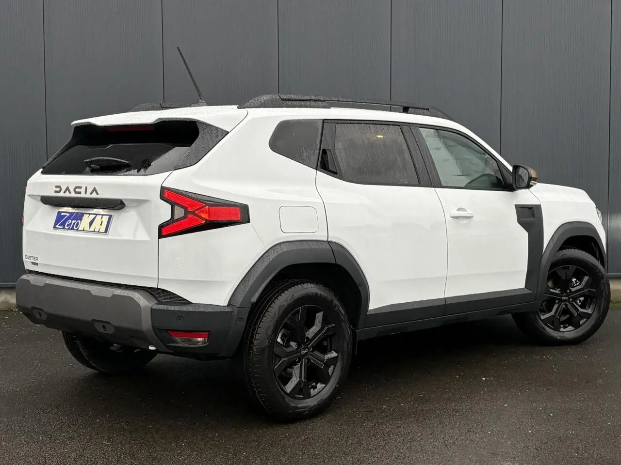 Vue 3/4 arrière droite du Dacia Duster blanc Glacier avec jantes noires et coques de rétroviseur brun cuivré.