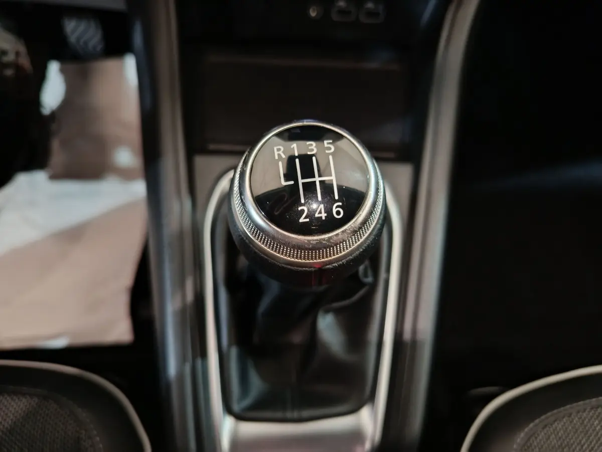 Gros plan sur le levier de vitesse manuel noir du Renault Captur Techno TCe 90 2024, intérieur sombre.