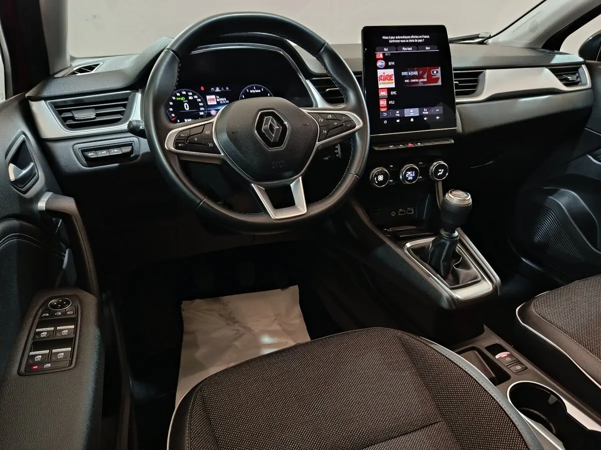 Intérieur noir du Renault Captur Techno TCe 90 2024, vue de face sur le volant, écran tactile et levier de vitesse manuel.