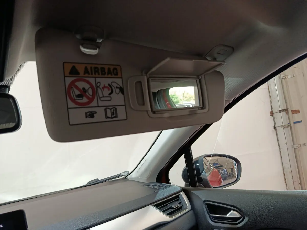 Détail du pare-soleil côté conducteur avec miroir ouvert et rétroviseur extérieur noir du Renault Captur rouge 2024.