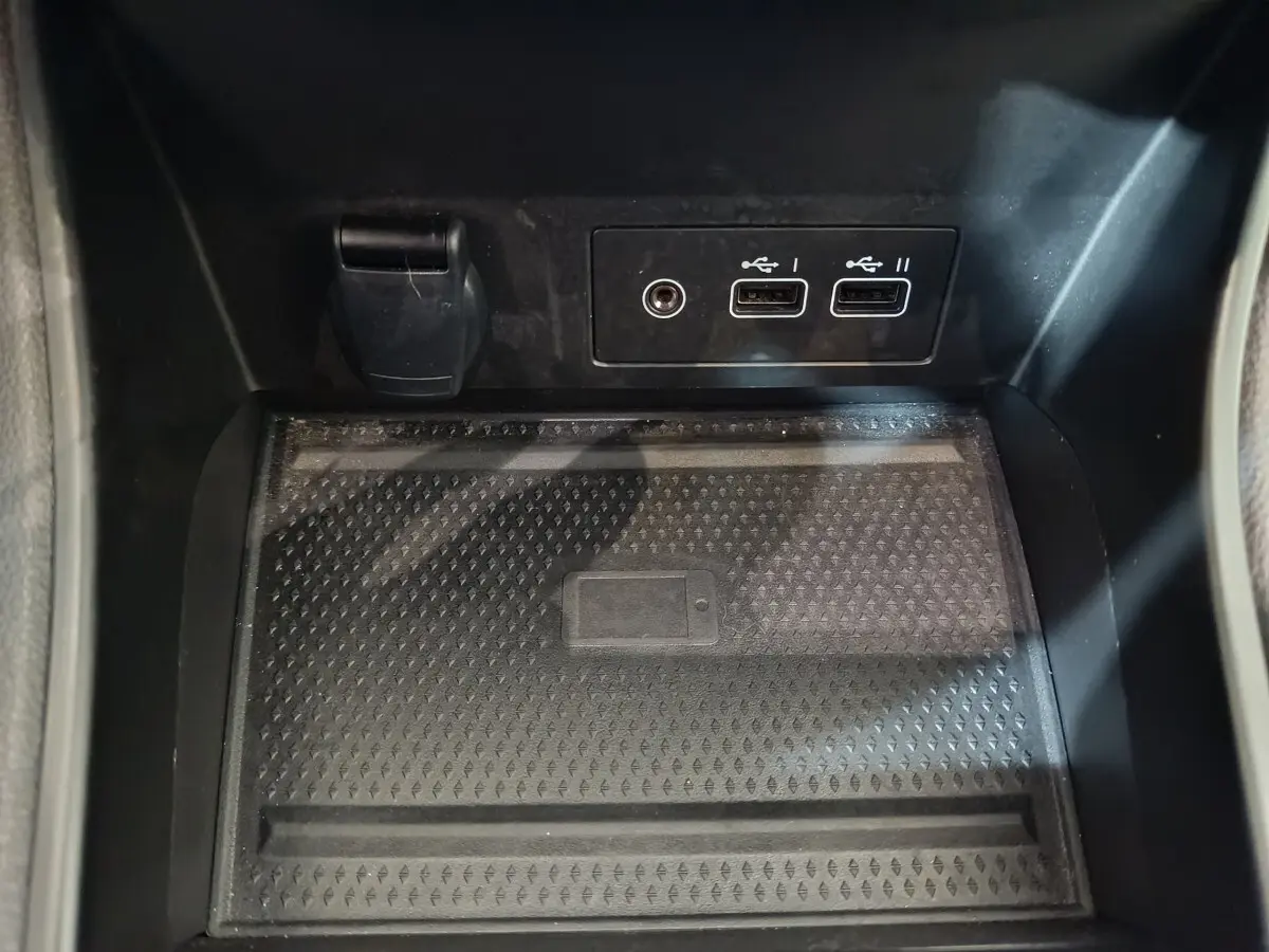 Zone de recharge par induction noire avec ports USB et prise 12V dans le coffre avant du Renault Captur rouge 2024