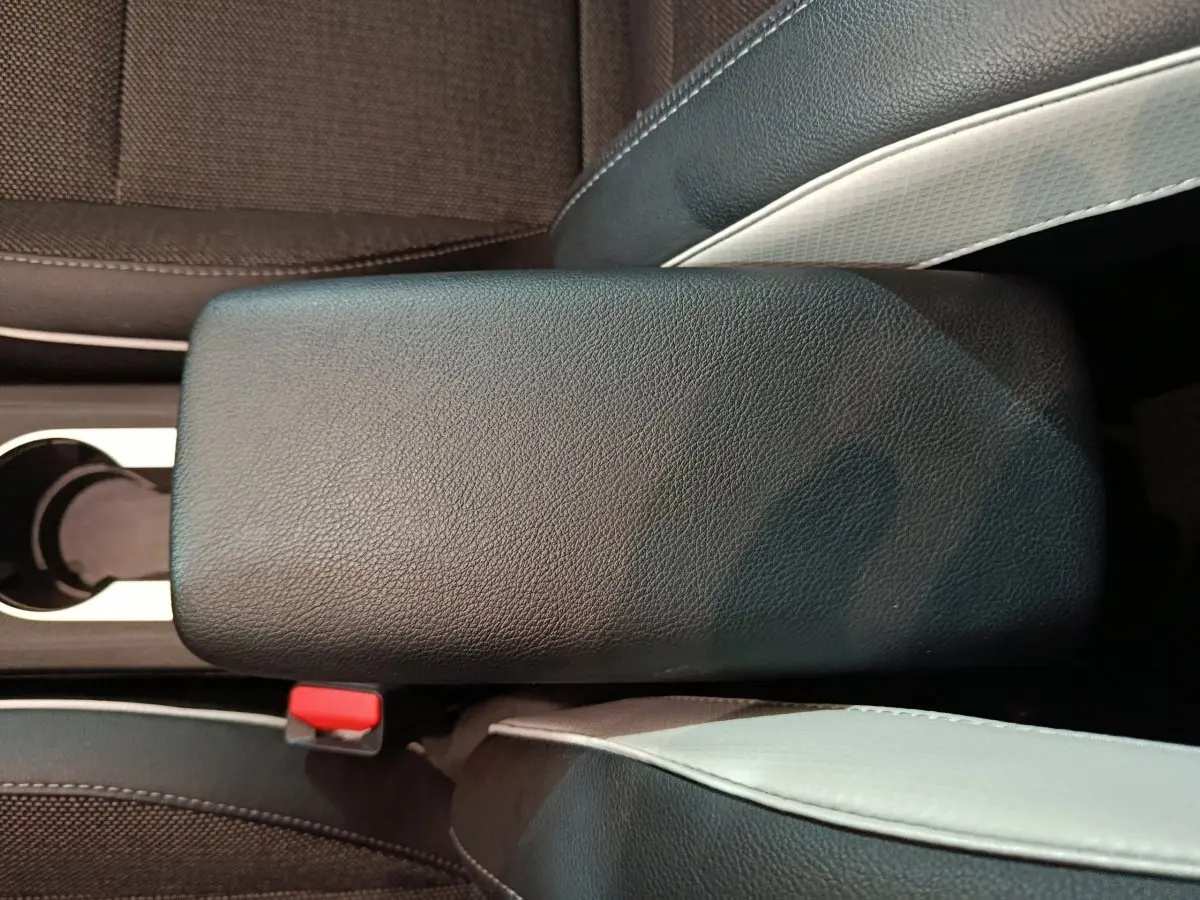 Gros plan sur l'accoudoir central noir entre les sièges avant du Renault Captur Techno TCe 90 rouge 2024.