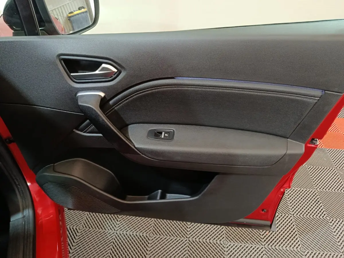 Vue rapprochée de la porte avant gauche rouge du Renault Captur 2024 avec panneau intérieur noir et commande de vitre.