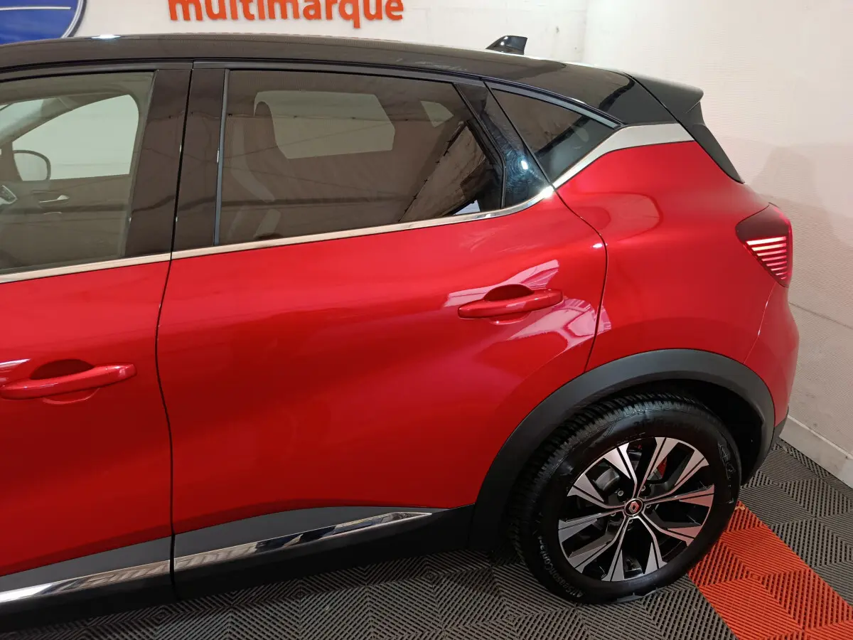 Vue latérale droite du Renault Captur rouge 2024 avec toit noir et jantes alliage distinctives.