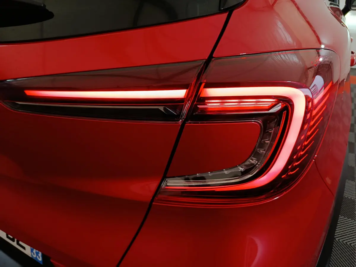 Gros plan sur le feu arrière droit rouge allumé du Renault Captur Techno TCe 90 2024 rouge brillant.