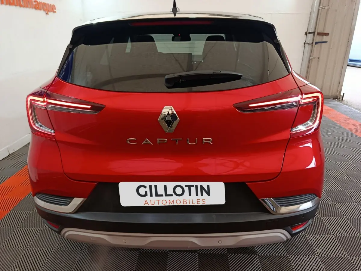 Vue arrière d'un Renault Captur rouge 2024 avec feux LED caractéristiques et logo central visible.