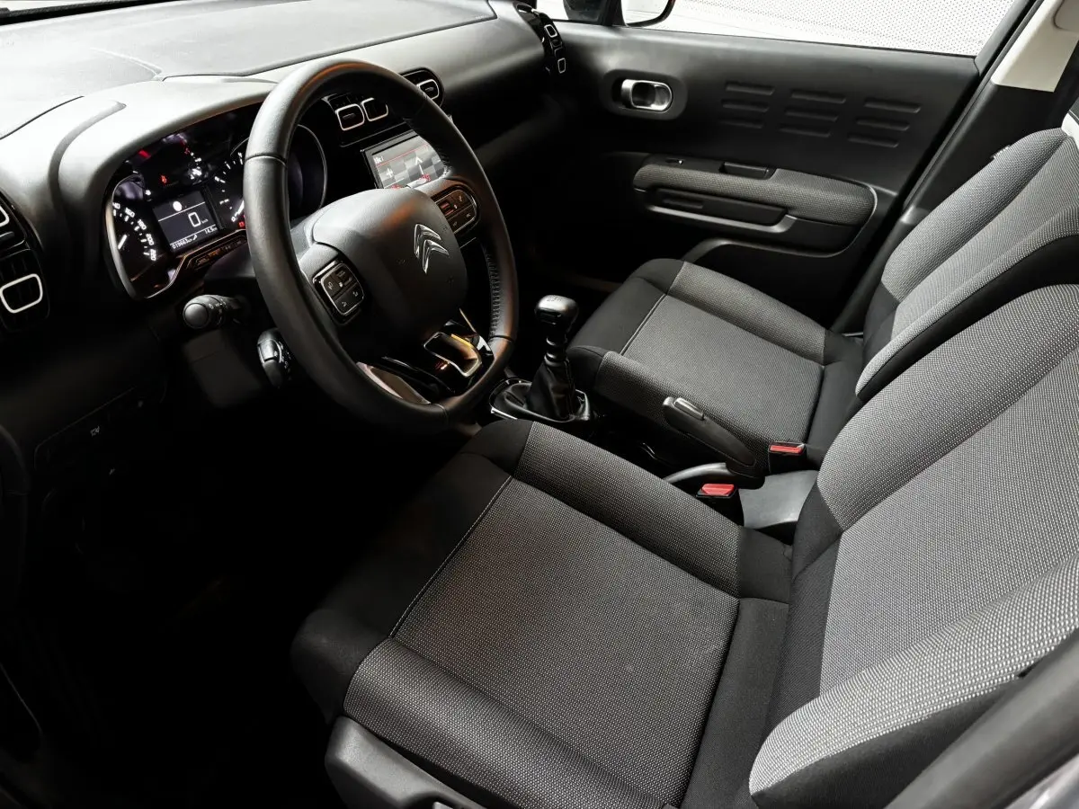 Intérieur avant du Citroën C3 Aircross 2024, vue côté conducteur, sièges gris et tableau de bord avec écran tactile.