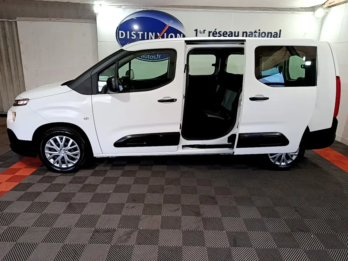 Vue latérale droite d'un Citroën Berlingo XL blanc 2019 avec porte coulissante ouverte en intérieur showroom.