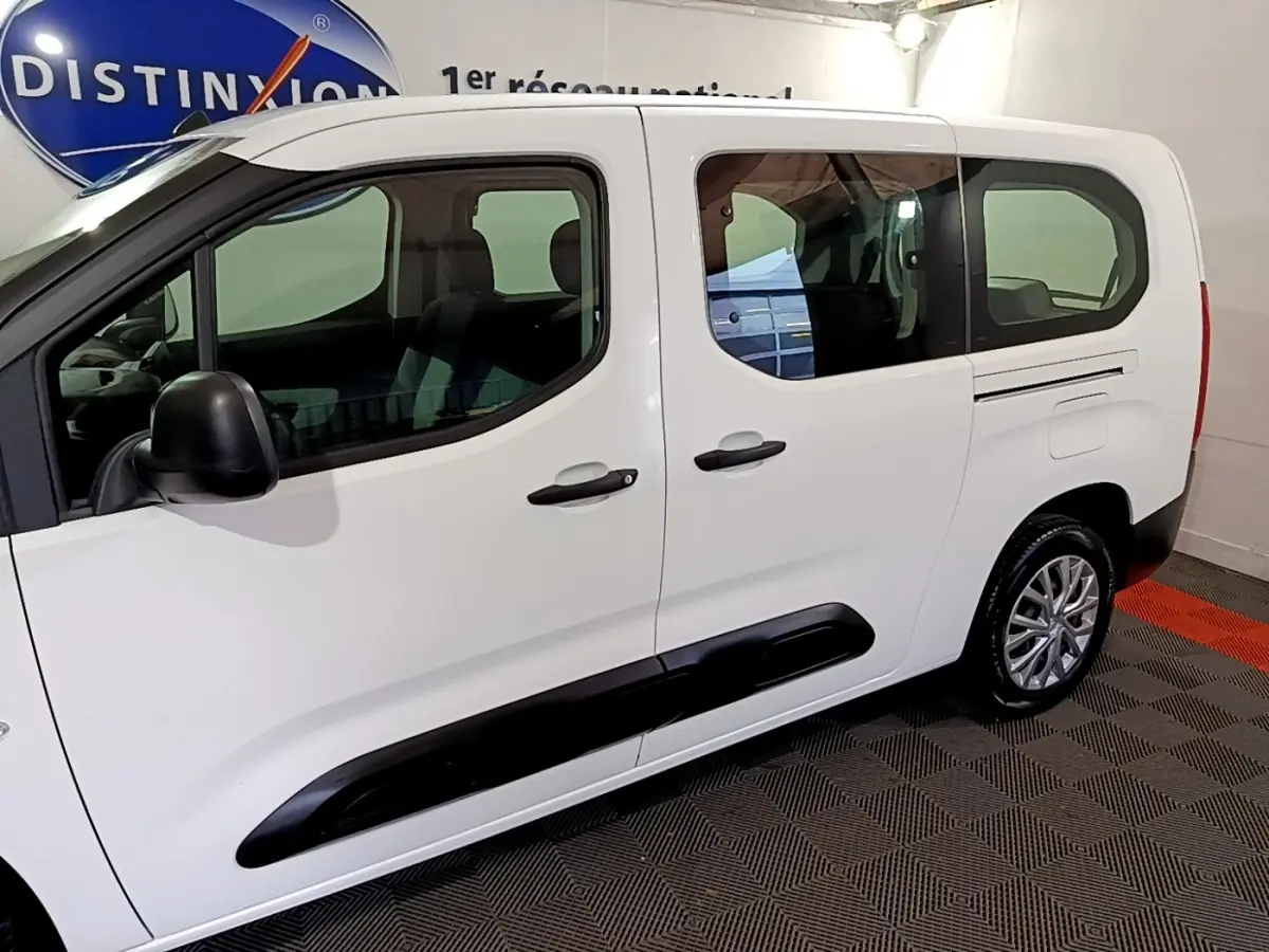 Profil côté gauche du Citroën Berlingo XL blanc de 2019, avec protection noire sur les portières et vitres teintées.