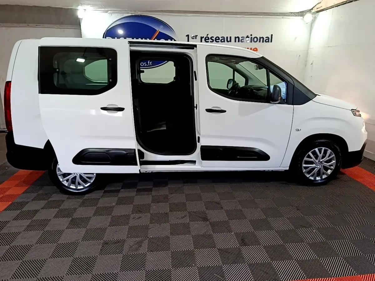 Vue de profil droit d’un Citroën Berlingo blanc XL avec porte coulissante ouverte, intérieur sombre visible.