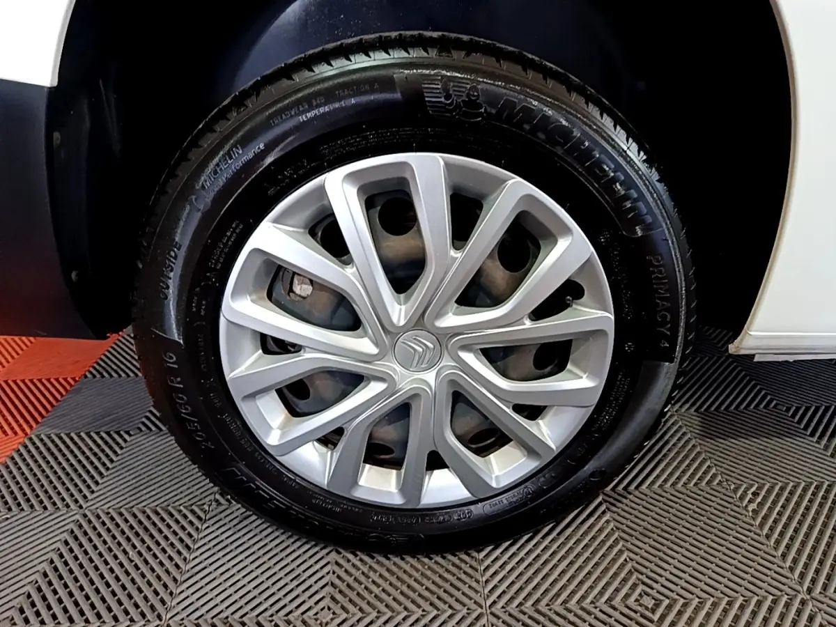 Gros plan sur la roue avant droite de la Citroën Berlingo XL blanche, mettant en valeur la jante en alliage et le pneu Michelin.