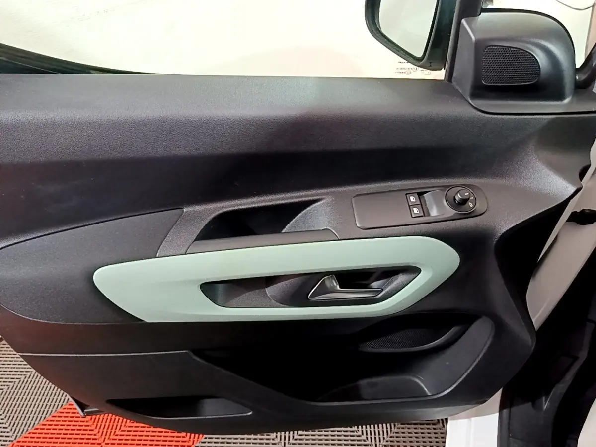 Vue intérieure du panneau de porte avant gauche du Citroën Berlingo blanc, avec poignée argentée et commandes électriques.