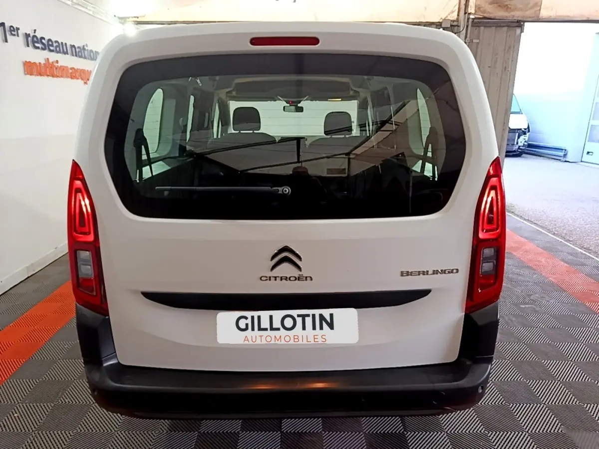 Vue arrière d'un Citroën Berlingo blanc XL, avec feux arrière allumés et logo visible sur un sol à motifs.
