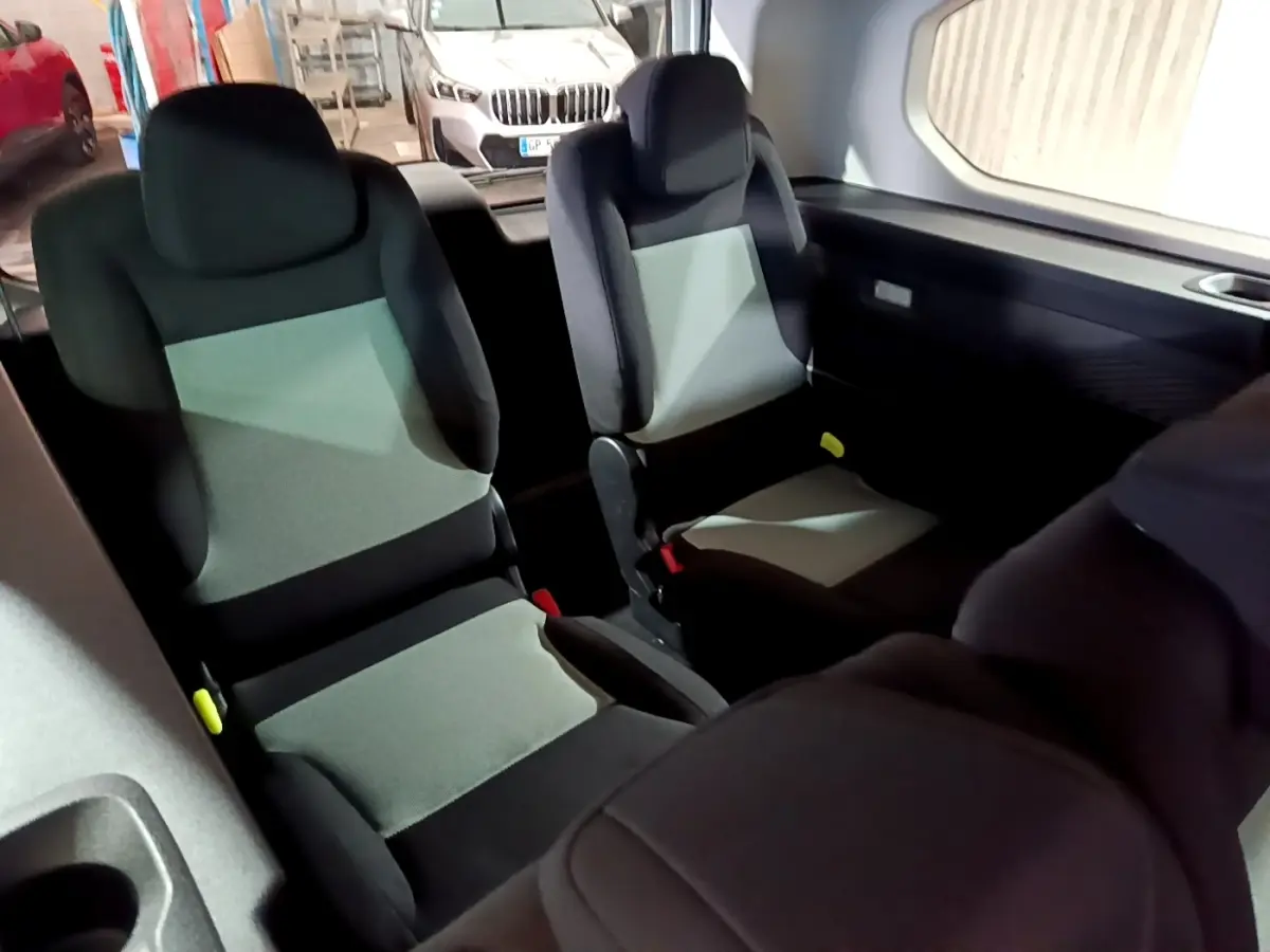 Vue intérieure arrière montrant les sièges passagers noirs et gris du Citroën Berlingo XL 2019.