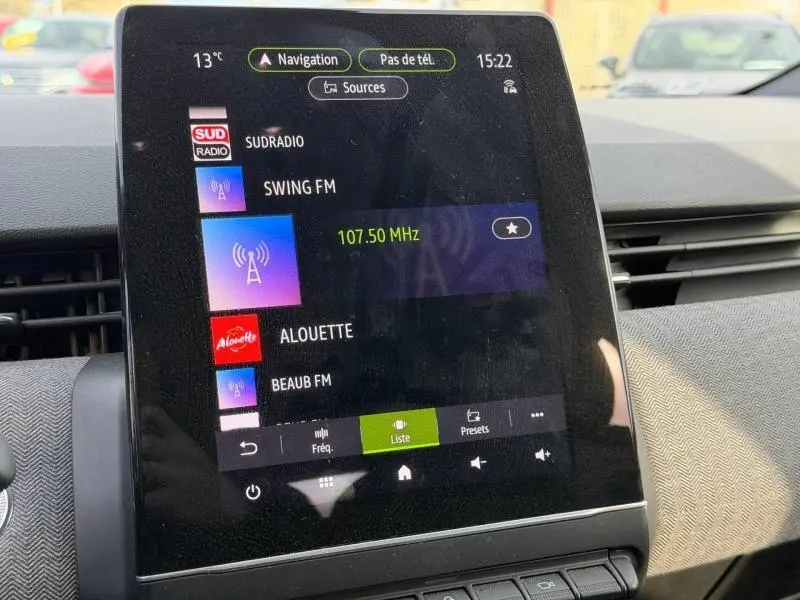 Écran tactile central de la Renault Clio 1.6 E-Tech 145ch full hybrid Techno 2025 affichant les stations radio, intérieur noir.