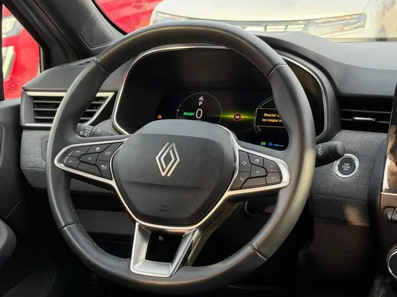 Vue intérieure centrée sur le volant de la Renault Clio 1.6 E-Tech 145ch gris Rafale avec tableau de bord numérique et bouton start/stop.