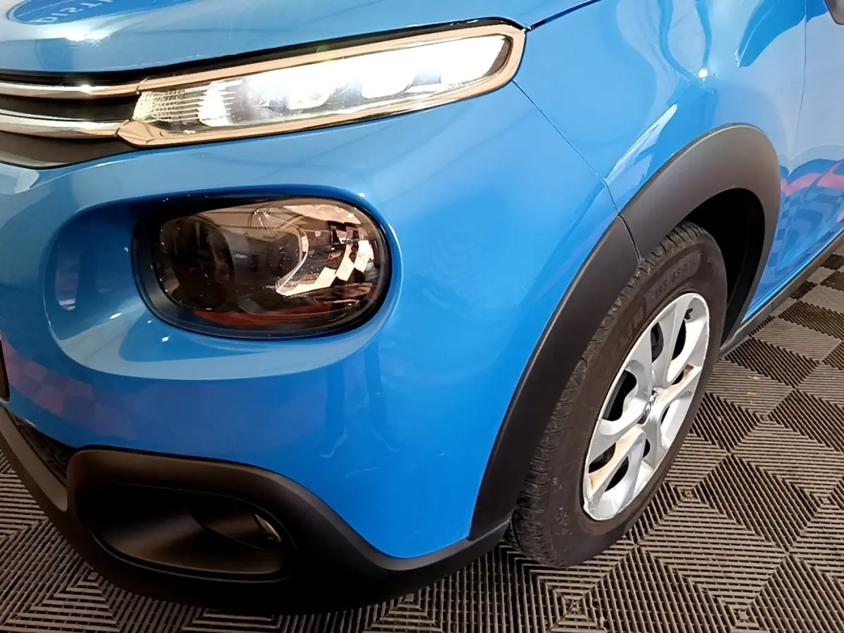 Gros plan sur l'avant droit bleu vif de la Citroën C3 2017, mettant en valeur ses phares distinctifs et la roue.
