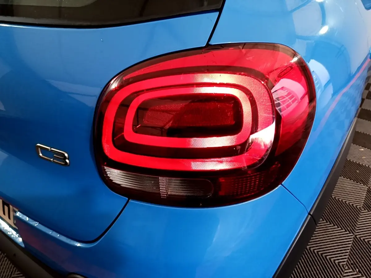 Gros plan sur le feu arrière droit rouge et la carrosserie bleue d'une Citroën C3 2017, version BlueHDi Feel Business.