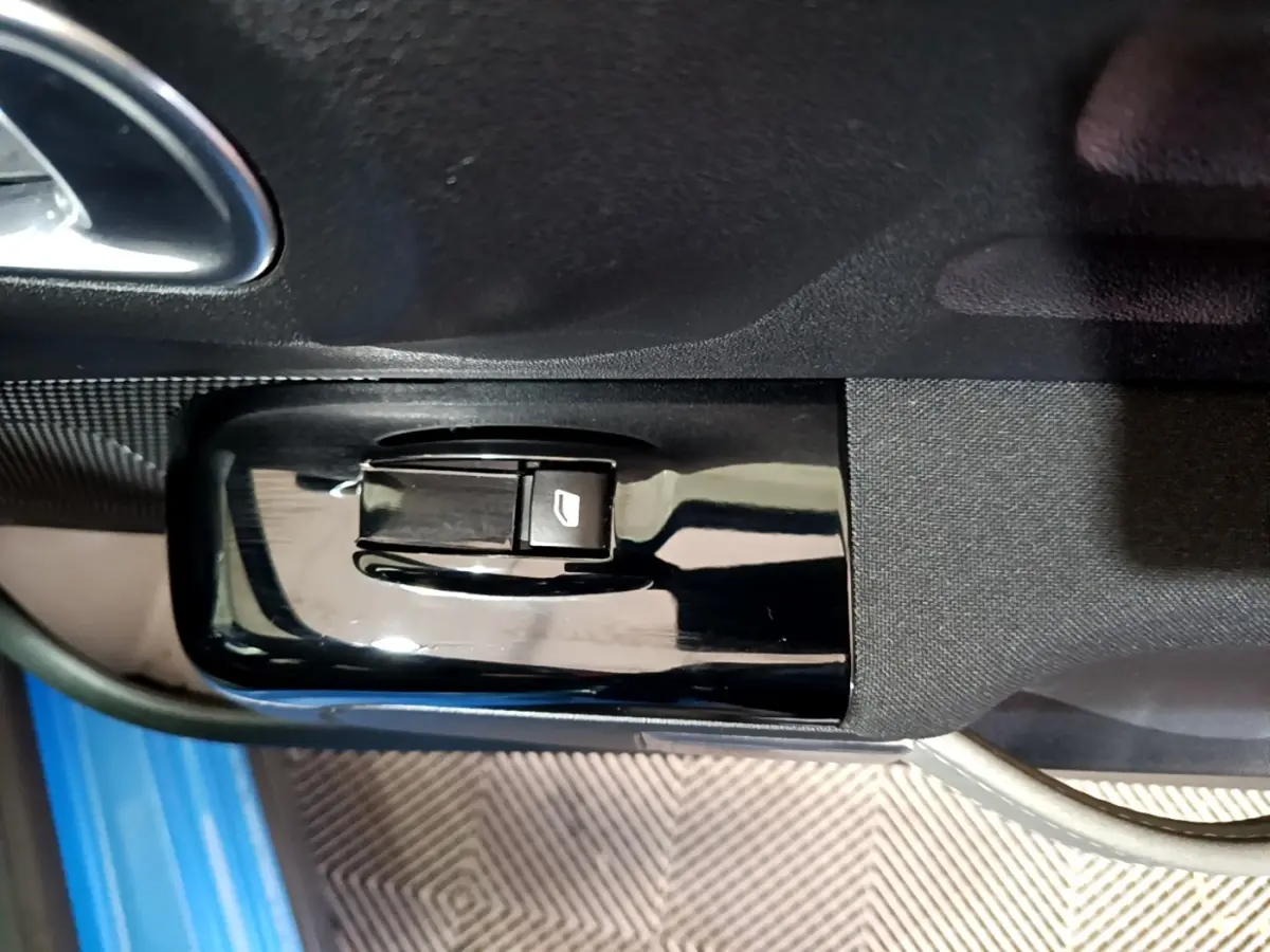 Bouton de commande de lève-vitre sur la porte côté conducteur d'une Citroën C3 bleu 2017, intérieur noir.