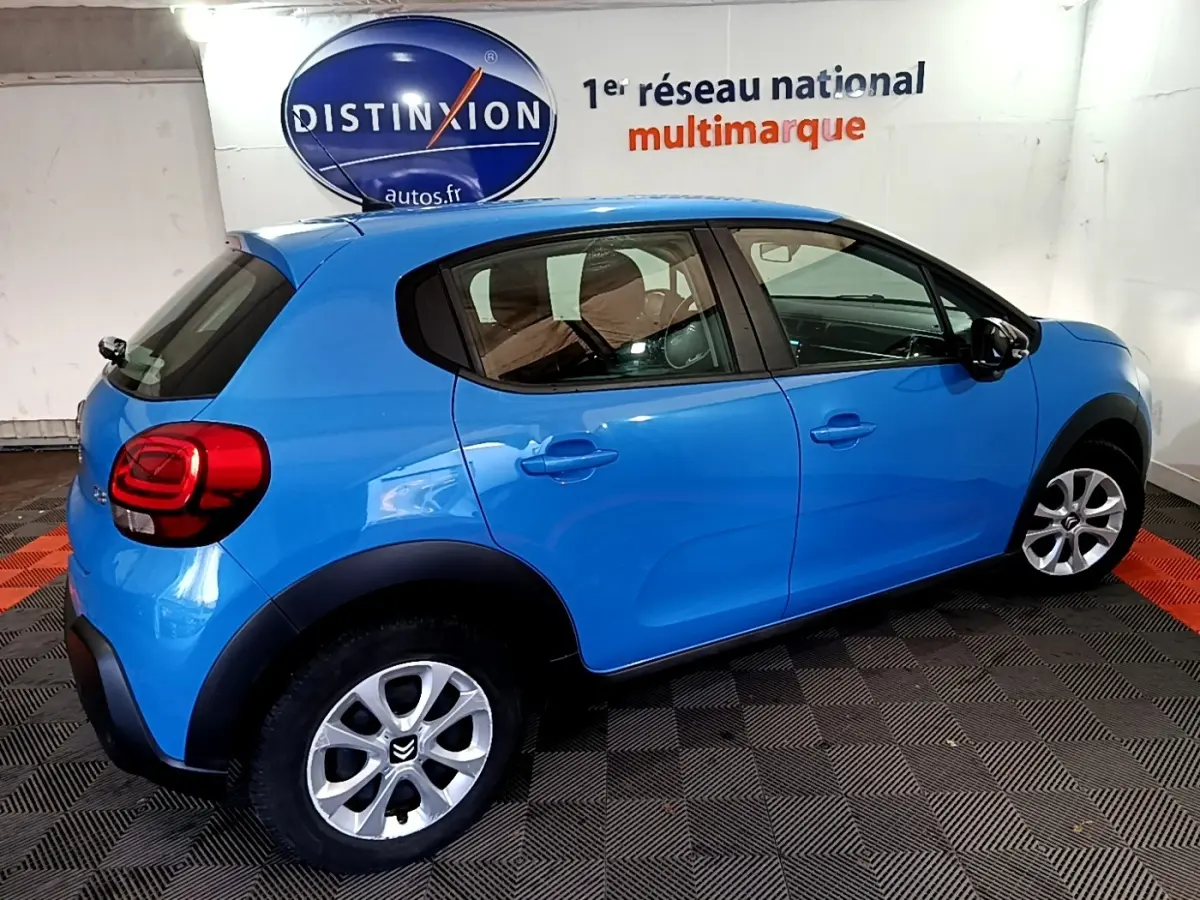 Citroën C3 bleu vue de profil droit en intérieur, avec jantes alliage et feux arrière arrondis rouges.