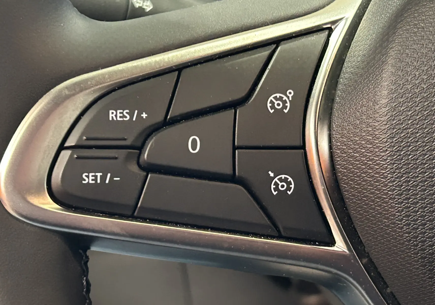 Gros plan sur les commandes de régulateur de vitesse au volant d'une Renault Clio V noire, version BlueDCI 100 Evolution.