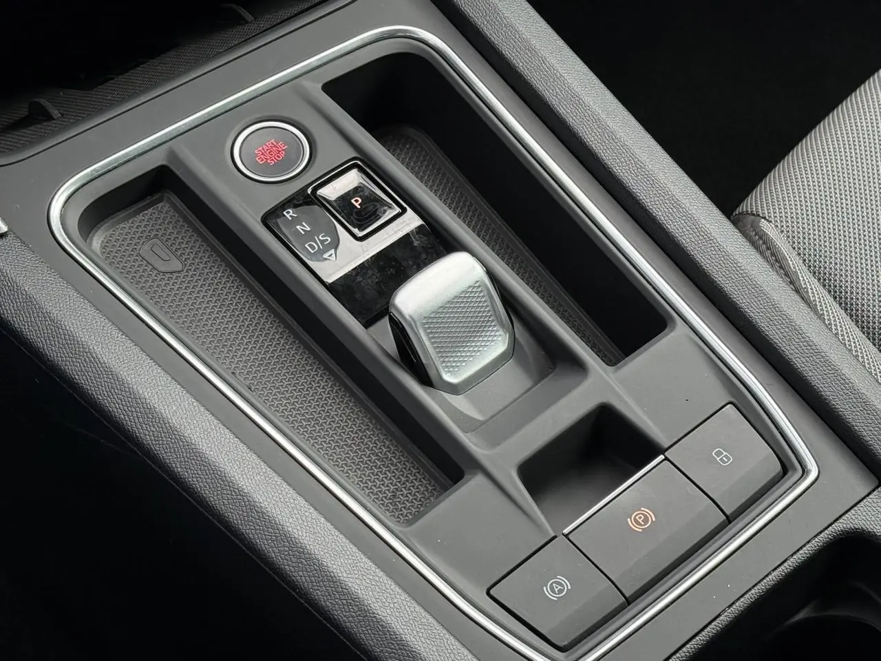 Gros plan sur la console centrale grise avec levier de vitesses automatique et bouton start/stop dans une SEAT Leon blanche.