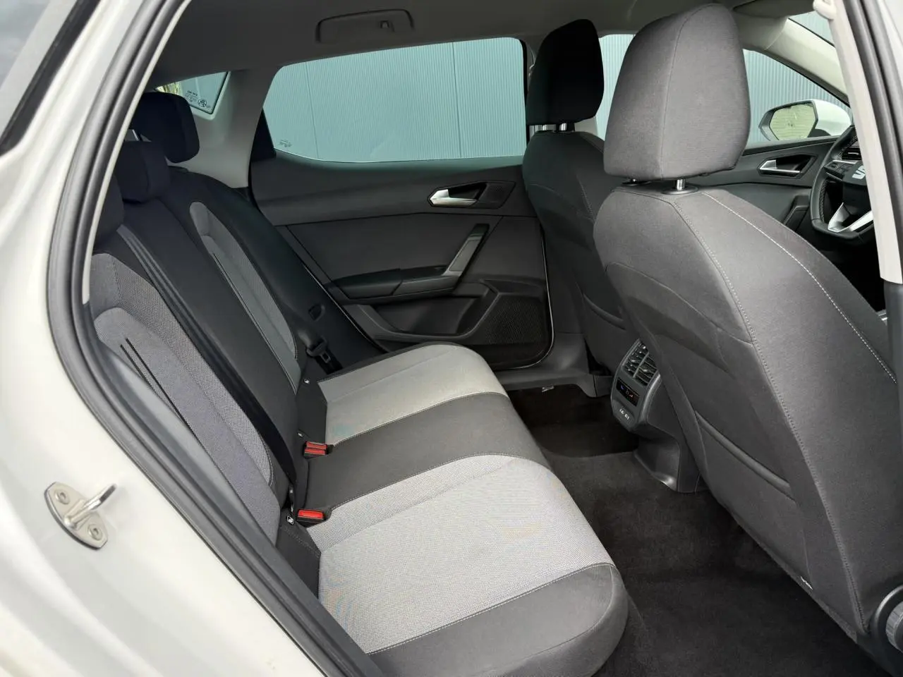 Vue intérieure côté gauche montrant la banquette arrière grise et noire du SEAT LEON blanc 2025.