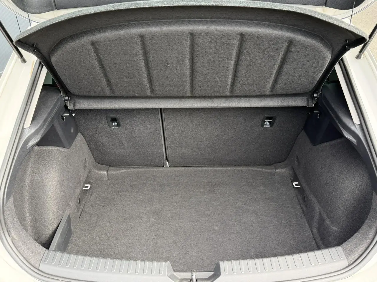 Coffre ouvert vu de l'arrière d'une SEAT LEON blanche, montrant un espace de chargement propre et spacieux.