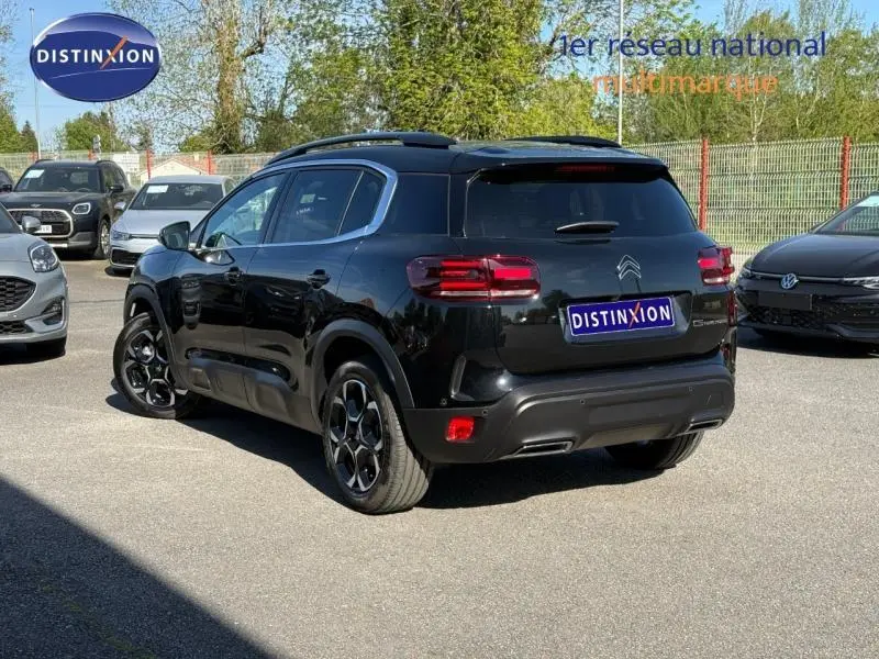 Vue 3/4 arrière droite du Citroën C5 Aircross noir Perla Nera avec jantes alu et barres de toit visibles.