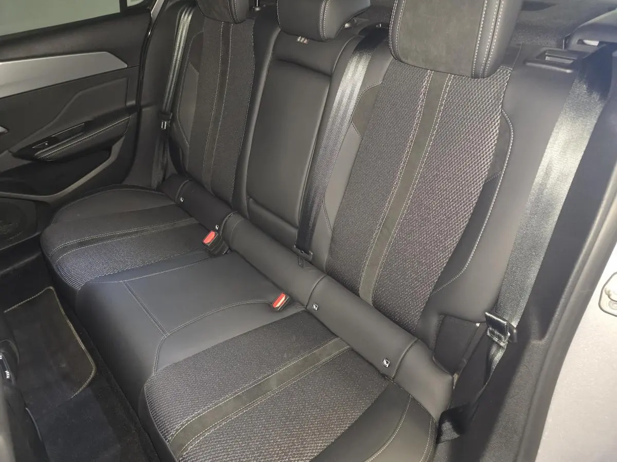 Vue intérieure côté gauche des sièges arrière noirs en tissu et cuir de la Peugeot 308 1.6 PHEV GT 2024.