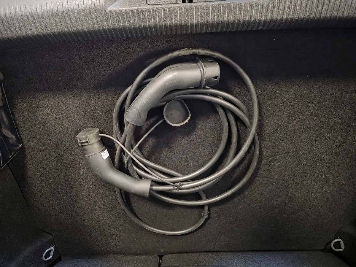 Gros plan sur câble de recharge noir enroulé dans le coffre d'une Peugeot 308 gris hybride rechargeable 2024.