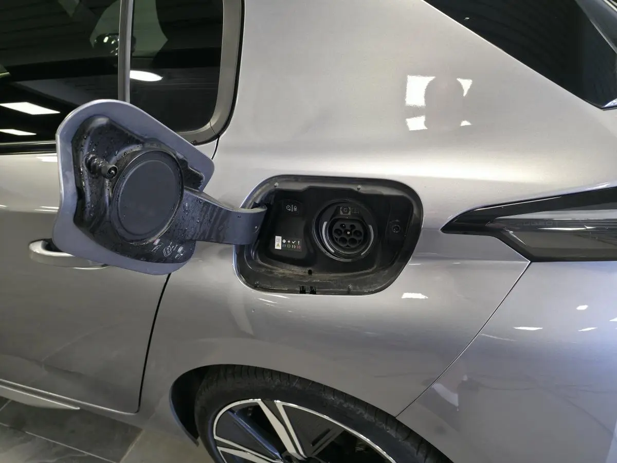 Prise de recharge ouverte côté gauche arrière d’une Peugeot 308 gris métallisé, avec jante alliage visible.