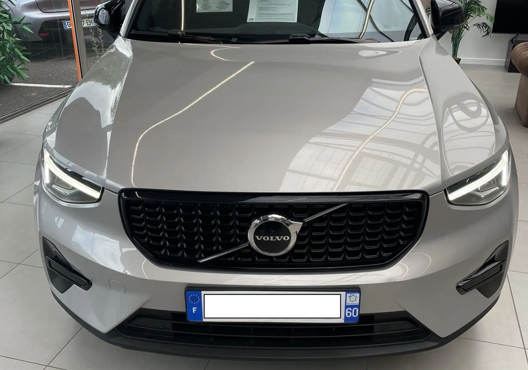 Vue frontale d'un Volvo XC40 B3 163ch Plus DCT 7 2023 en argent aurore métallisé avec calandre noire et phares LED allumés.