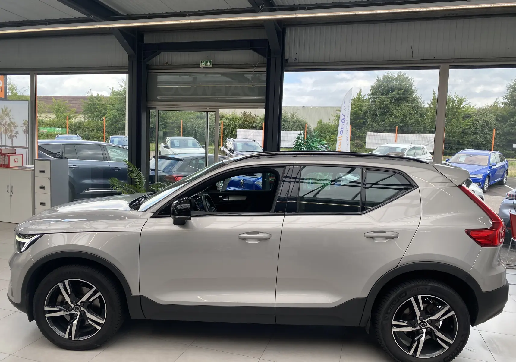 Profil côté gauche du Volvo XC40 B3 163ch Plus 2023 en argent aurore métallisé, avec jantes alliage et toit noir contrasté.