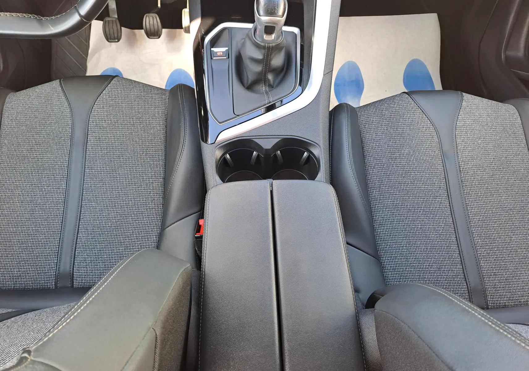 Vue plongeante sur l'intérieur du Peugeot 3008 2019, montrant la console centrale noire et les sièges tissu gris avec cuir noir.