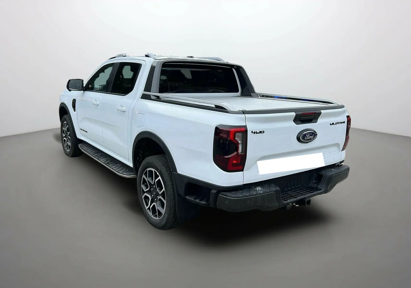 Ford Ranger 2025 blanc glacier en 3/4 arrière droit, version Wildtrak Plus avec benne couverte et jantes alliage.