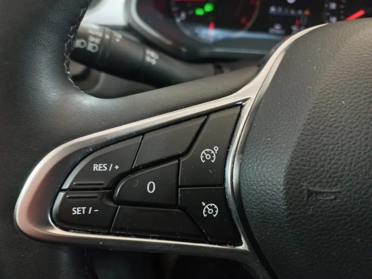 Gros plan sur les commandes du régulateur de vitesse au volant noir du Renault Captur Business gris clair 2020.