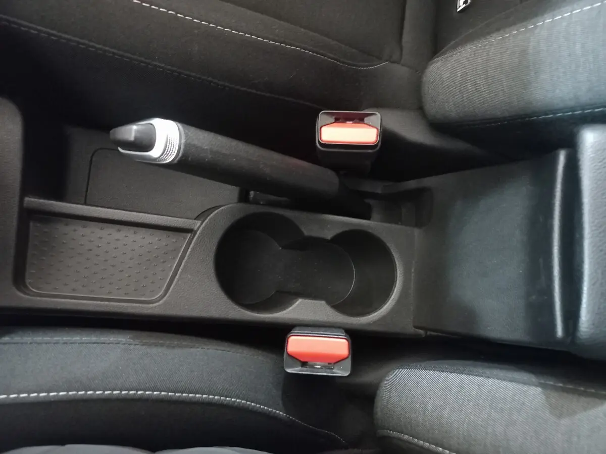 Vue rapprochée de la console centrale noire avec frein à main manuel et deux ceintures rouges dans un Renault Captur gris clair 2020.
