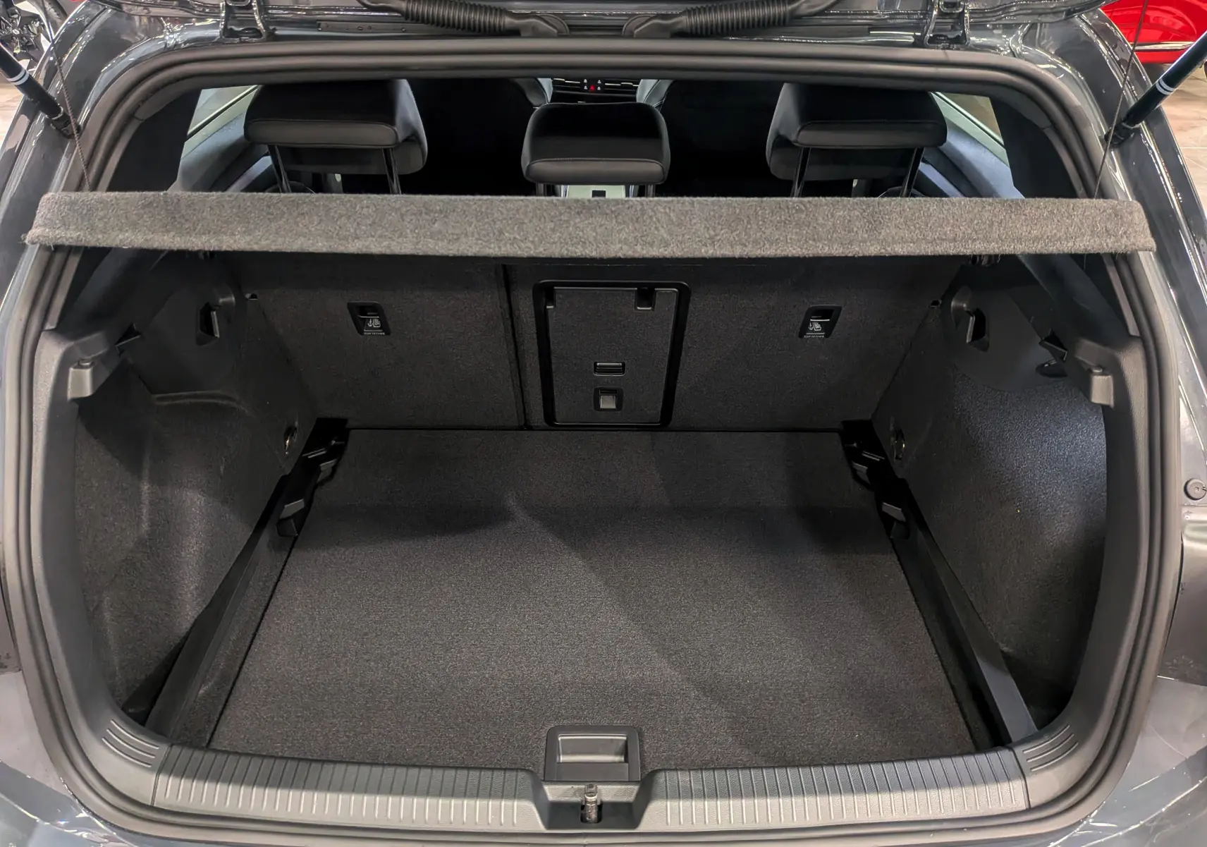 Coffre ouvert d'une Volkswagen Golf 1.5 eTSI gris dauphin, vue arrière montrant l'espace de chargement et les sièges arrière.