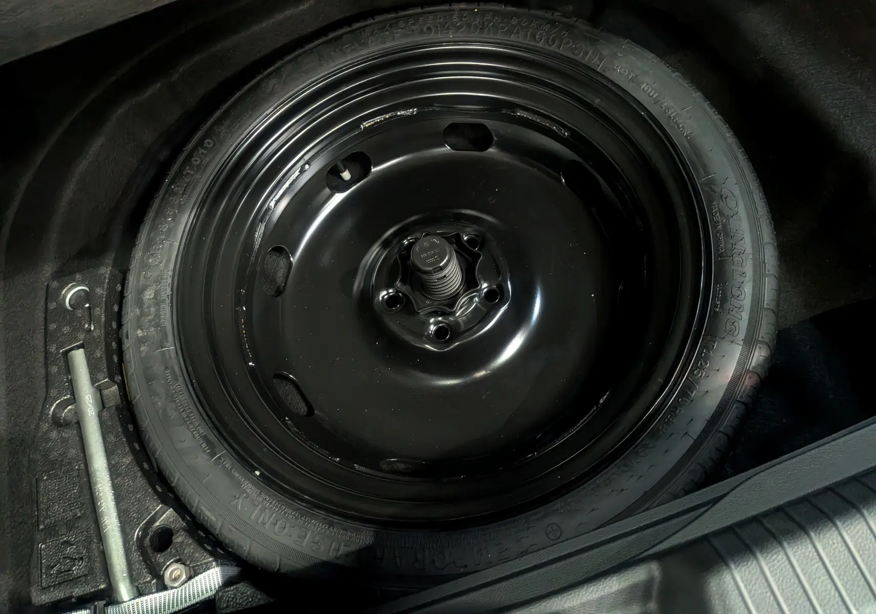 Gros plan sur la roue de secours noire dans le coffre d'une Volkswagen Golf 1.5 eTSI 2025 gris dauphin.