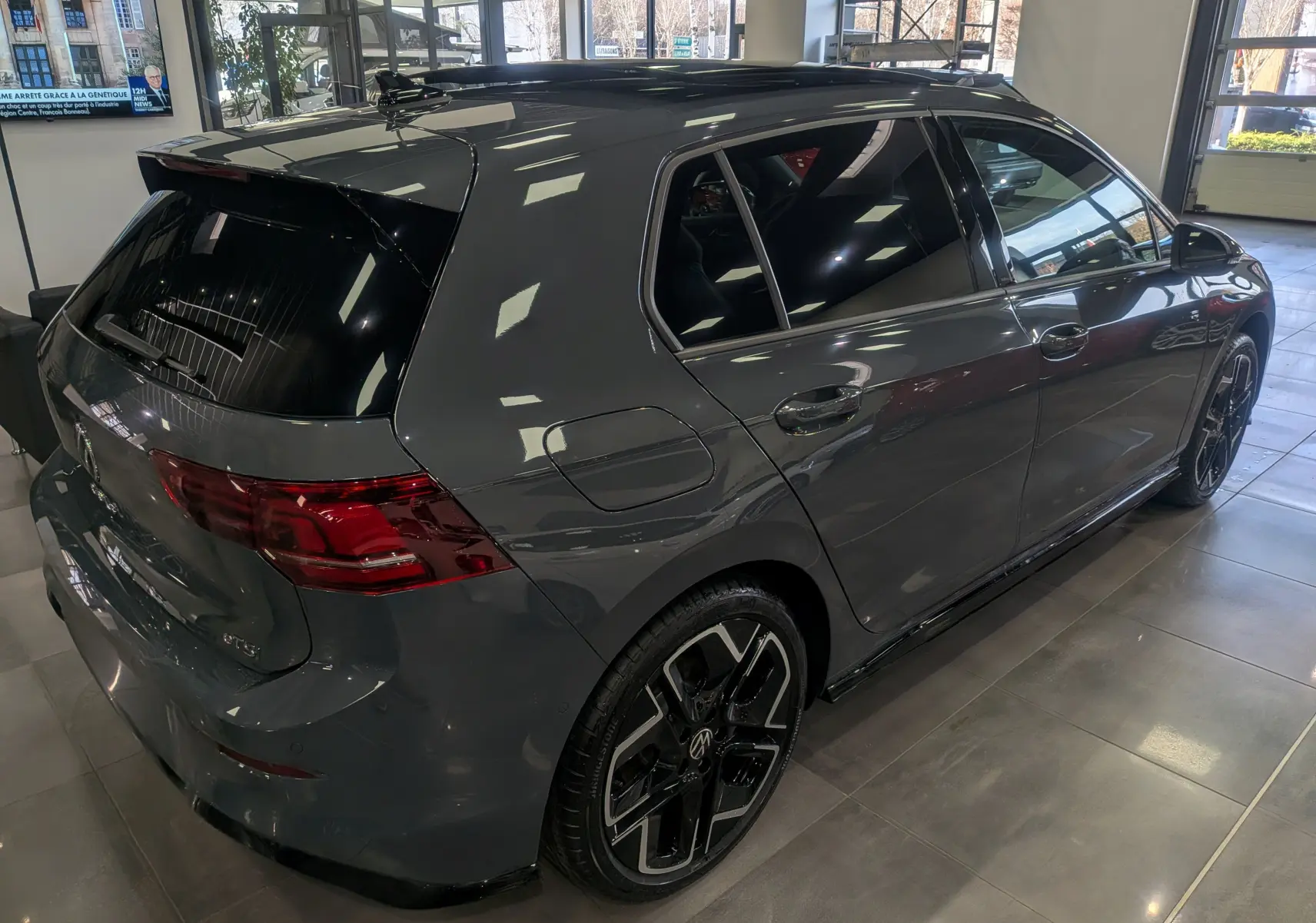 Volkswagen Golf 1.5 eTSI R-Line gris dauphin vue 3/4 arrière droit en showroom avec jantes noires distinctives.