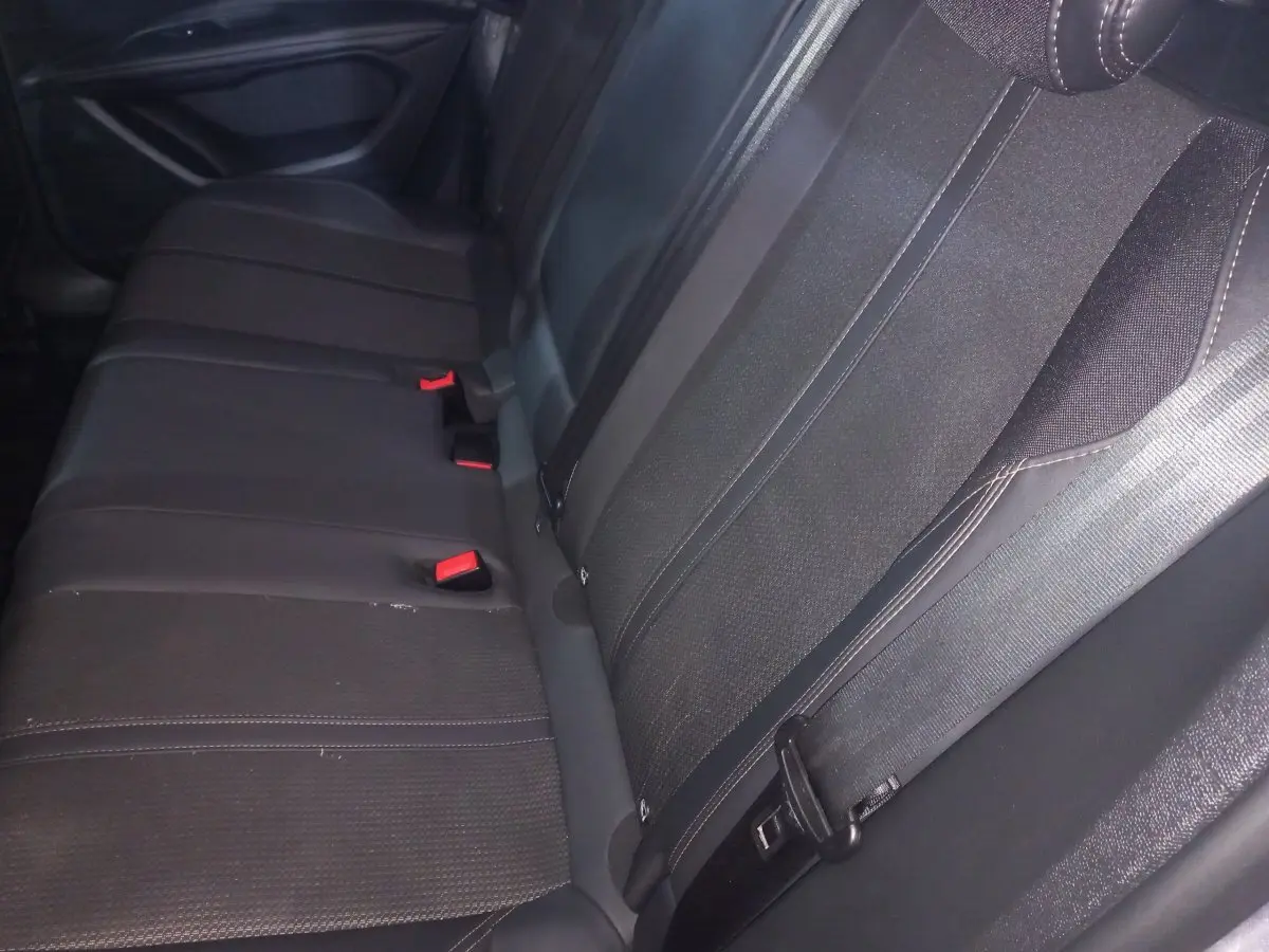 Vue rapprochée de la banquette arrière noire du Peugeot 3008, montrant les ceintures et les boucles rouges.