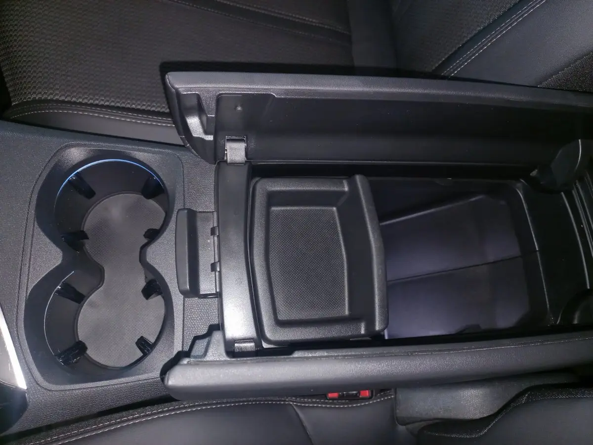 Vue rapprochée de la console centrale ouverte avec porte-gobelets et rangement noir dans un Peugeot 3008 gris clair 2022.